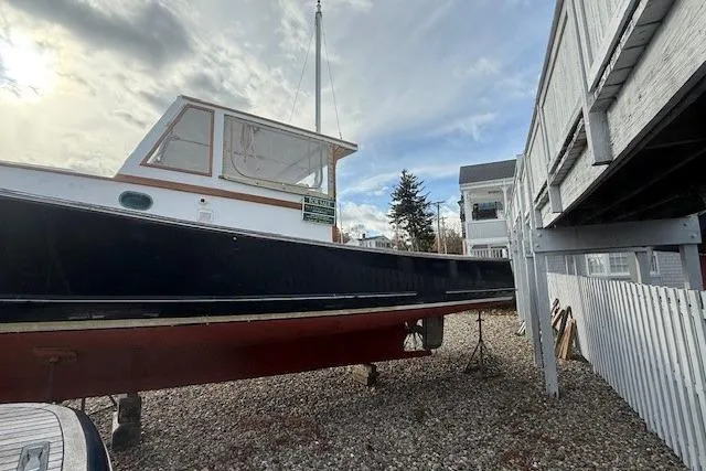 Slide: The Image of 1975 Jarvis Newman 32 DEC boat on gravel, near white fence and buildings. - 76