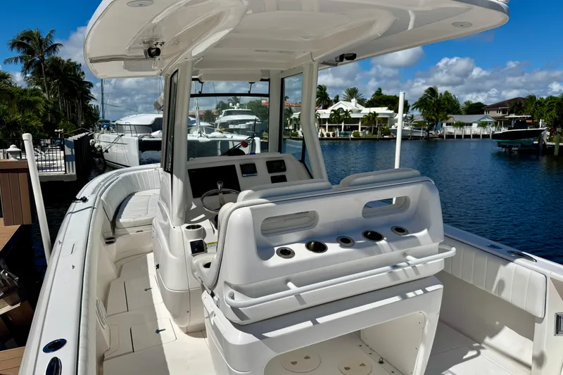 Slide: The Image of 2014 Intrepid 327 Center Console boat docked by waterfront homes under blue sky. - 16