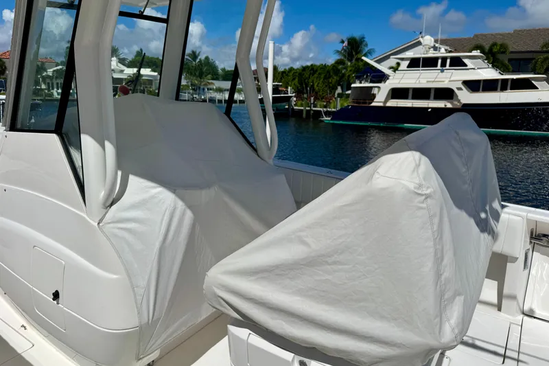 Slide: The Image of 2014 Intrepid 327 Center Console boat with covered seats, docked near luxury yachts. - 23