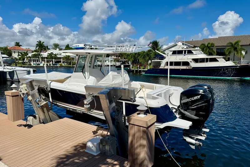 Slide: The Image of 2014 Intrepid 327 Center Console boat docked by waterfront homes under blue sky. - 3