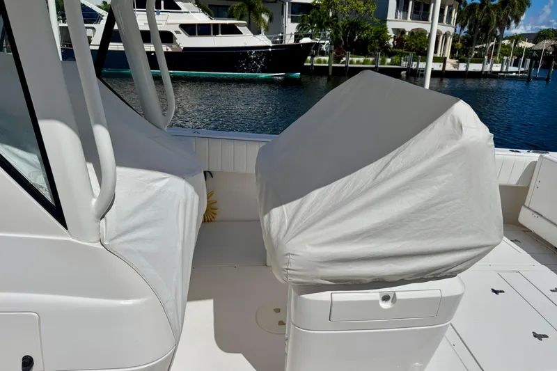 Slide: The Image of 2014 Intrepid 327 Center Console boat interior with covered seats, docked near luxury yachts. - 8