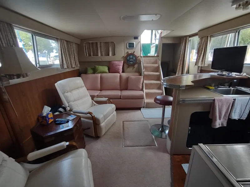 Slide: The Image of 1987 Chris-Craft 381 Catalina interior with cozy seating, TV, and kitchenette. - 17