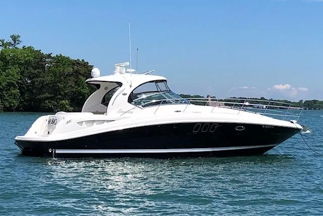 Slide: The Image of 2008 Sea Ray 400 Sundancer yacht on calm water, sunny day, lush greenery in background. - 2