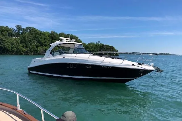 Slide: The Image of 2008 Sea Ray 400 Sundancer yacht on clear blue water, near a lush green shoreline. - 25