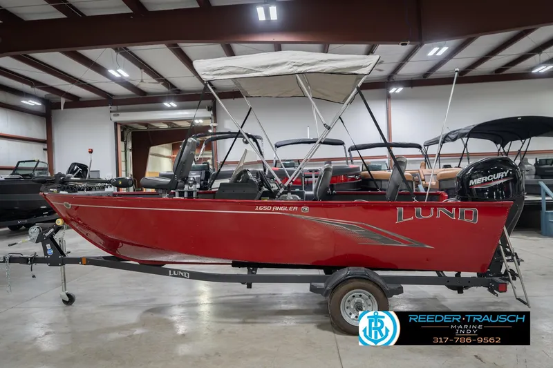 Slide: The Image of 2023 Lund 1650 Angler SS boat in showroom, red exterior, with Mercury engine. - 11