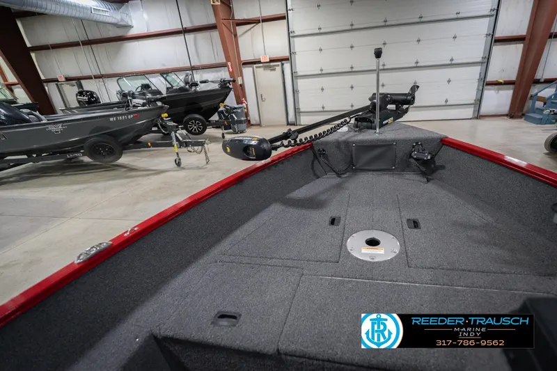 Slide: The Image of 2023 Lund 1650 Angler SS boat interior in showroom, featuring trolling motor and carpeted deck. - 26