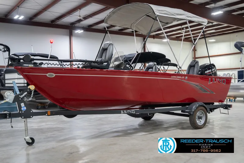 Slide: The Image of 2023 Lund 1650 Angler SS boat in showroom, red exterior, equipped with canopy and trailer. - 4