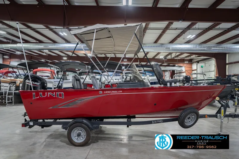 Slide: The Image of 2023 Lund 1650 Angler SS boat in showroom, red exterior, canopy, trailer included. - 7