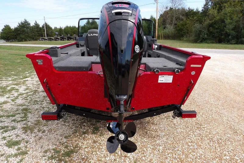 Slide: The Image of 2026 Lund 1775 Adventure Sport boat, red exterior, rear view with motor, parked on gravel. - 11