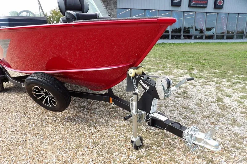 Slide: The Image of 2026 Lund 1775 Adventure Sport boat on trailer, red hull, parked on gravel. - 48