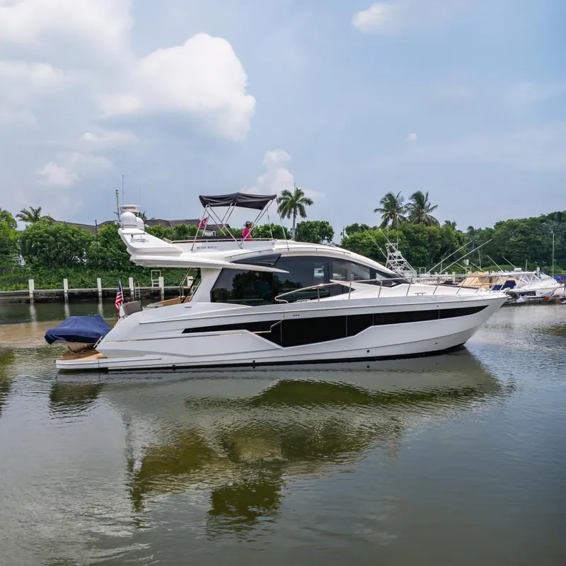 Slide: The Image of 2017 Galeon 510 Sky yacht on calm water, surrounded by lush greenery and palm trees. - 0
