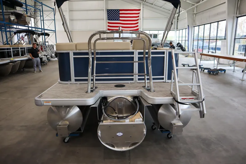 Slide: The Image of 2026 Godfrey Sweetwater 2286 C Tritoon in showroom with American flag backdrop. - 12