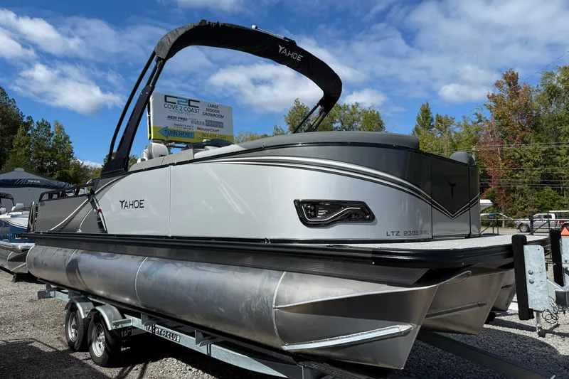 The Image of 2026 Tahoe Pontoon LTZ Versatile Rear Lounger on trailer, displayed outdoors under blue sky. - 0