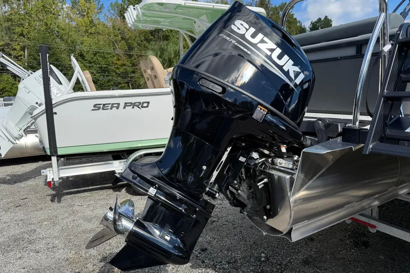 Slide: The Image of 2026 Tahoe Pontoon LTZ Versatile Rear Lounger with Suzuki outboard motor, parked outdoors. - 2