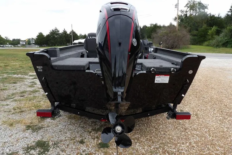 Slide: The Image of 2026 Lund 1775 Adventure SS boat with powerful outboard motor, parked on gravel. - 2