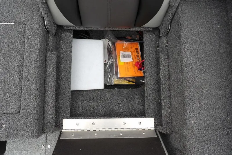 Slide: The Image of Storage compartment in 2026 Lund 1775 Adventure SS boat, featuring carpeted interior and documents. - 21