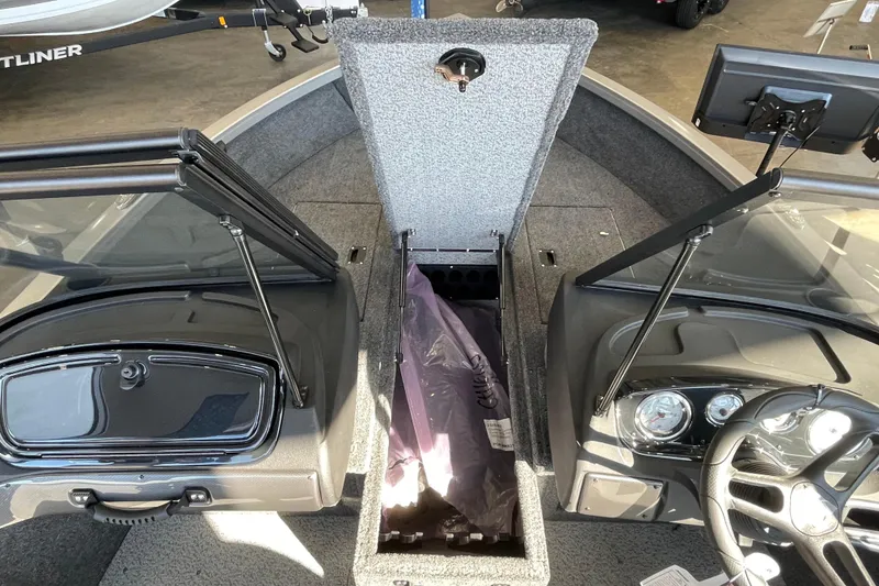 Slide: The Image of 2026 Crestliner 1650 Hawk boat interior with open storage compartment and dashboard view. - 14