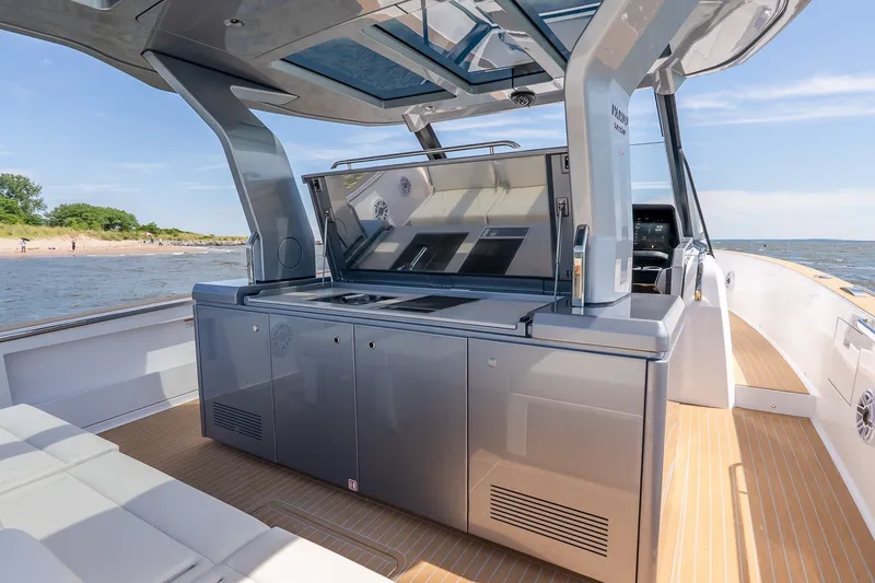 Slide: The Image of Luxurious 2027 Pardo Yachts P43R with sleek outdoor kitchen on deck, cruising near shoreline. - 18