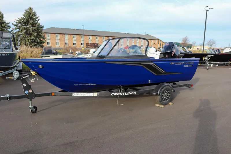 Slide: The Image of 2026 Crestliner 1750 Hawk boat in blue on a trailer, parked outdoors. - 2