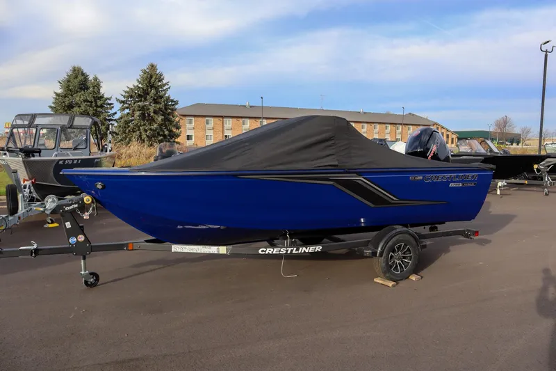 Slide: The Image of 2026 Crestliner 1750 Hawk boat, blue with black cover, parked on a trailer. - 4