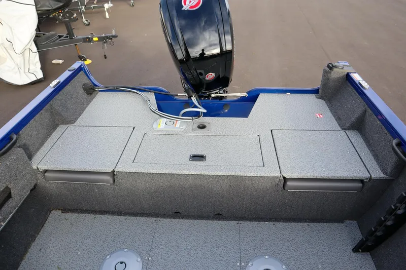 Slide: The Image of 2026 Crestliner 1750 Hawk boat interior with motor, featuring storage compartments and carpeted flooring. - 6