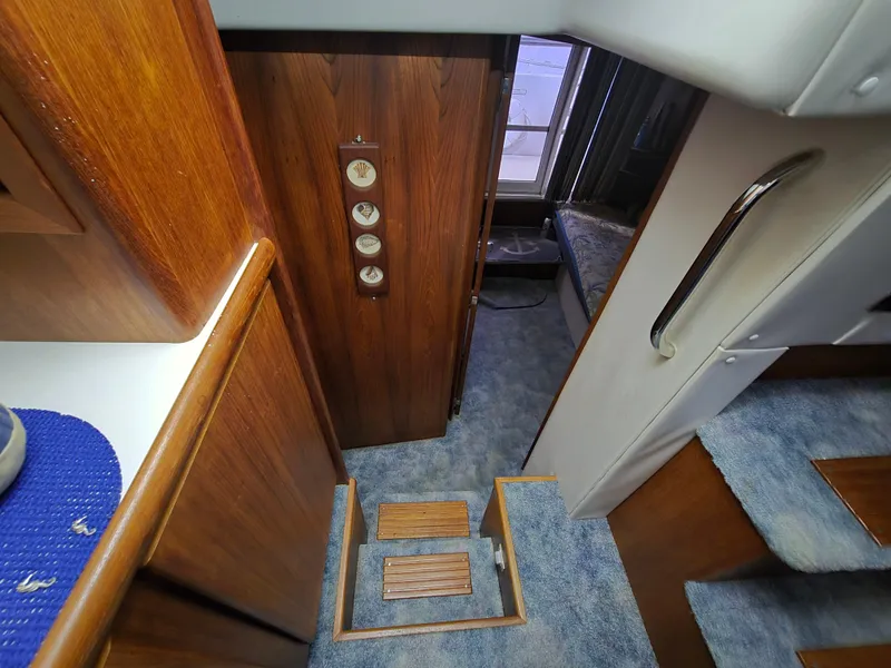 Slide: The Image of 1994 Carver 390 interior with wooden paneling, blue carpet, and stairs leading to cabin. - 33