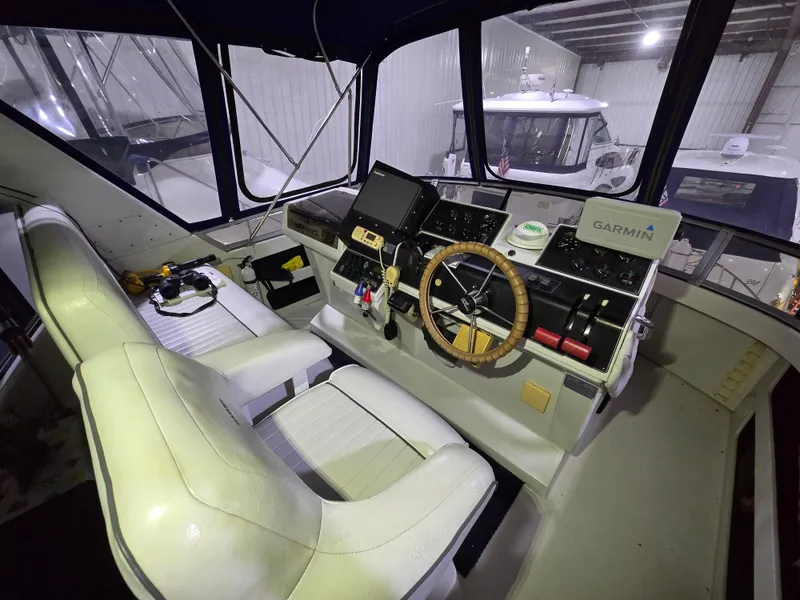 Slide: The Image of 1994 Carver 390 boat cockpit with steering wheel, Garmin navigation, and dual seats in a marina. - 20