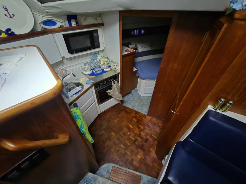 Slide: The Image of 1994 Carver 390 yacht interior with kitchen, wood cabinetry, and cozy sleeping area. - 27