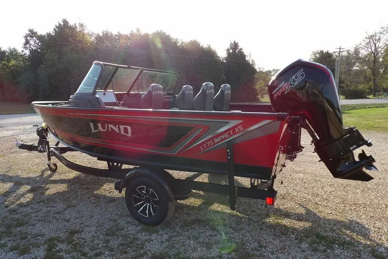Slide: The Image of 2026 Lund 1775 Impact XS Sport boat on trailer, red and black design, parked outdoors. - 18