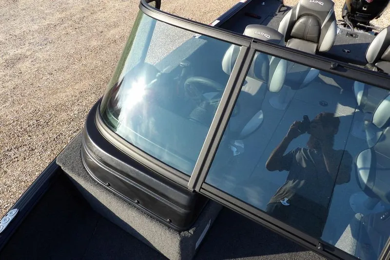 Slide: The Image of 2026 Lund 1775 Impact XS Sport boat with windshield and seating, reflecting sunlight. - 44