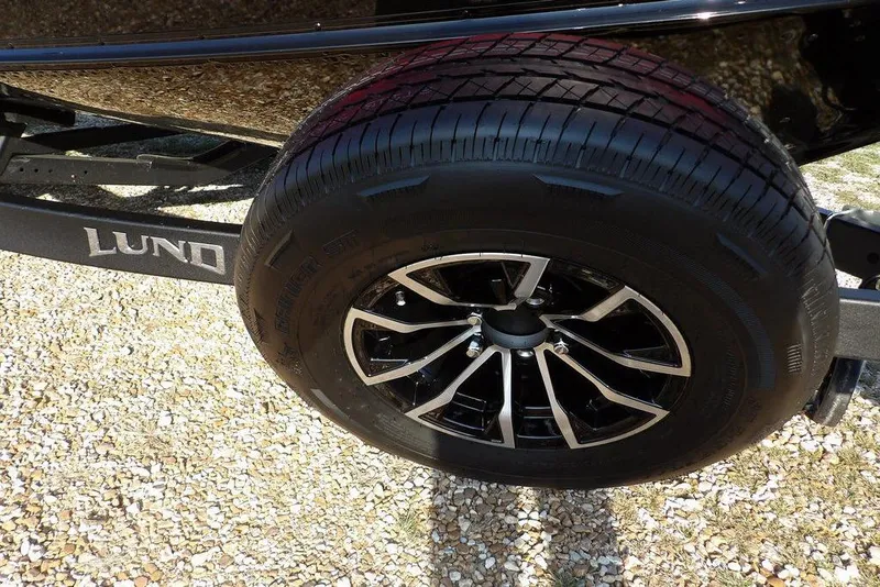 Slide: The Image of 2026 Lund 1775 Impact XS Sport trailer wheel on gravel surface. - 60