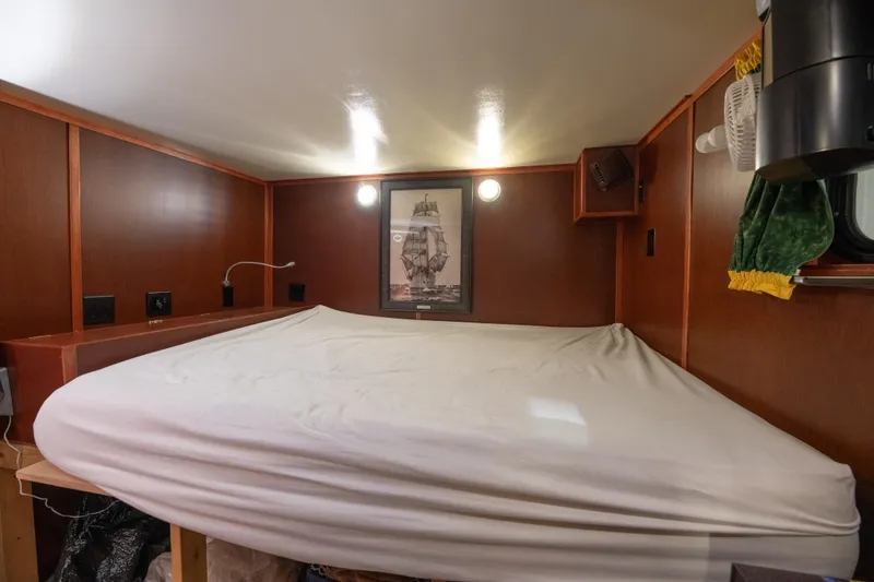 Slide: The Image of Cozy cabin bedroom in a 1993 Custom Steel Trawler with wooden walls and a framed ship picture. - 20