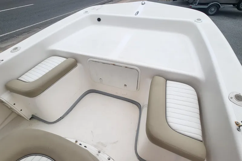 Slide: The Image of 2018 Sundance B18CCR boat interior with cushioned seating and storage compartment. - 2