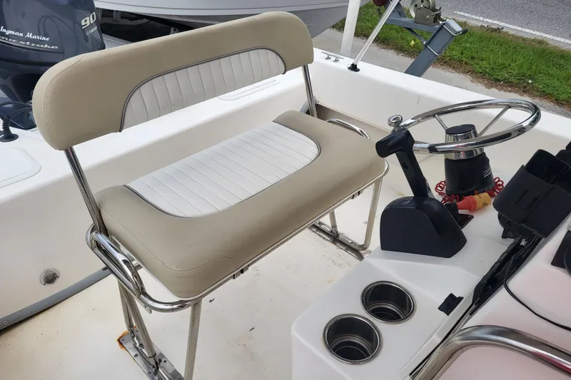 Slide: The Image of 2018 Sundance B18CCR boat interior with steering wheel, beige seating, and cup holders. - 6