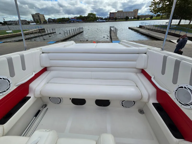 Slide: The Image of 1995 Fountain 38 Sport Cruiser with white seating, docked by a scenic waterfront. - 24