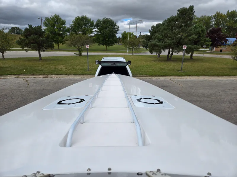 Slide: The Image of 1995 Fountain 38 Sport Cruiser boat on trailer, parked in a lot with trees. - 33