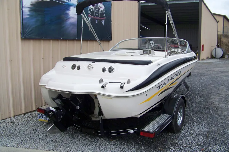 Slide: The Image of 2005 Tahoe Q4 I/O boat on trailer, parked near a metal building. - 1