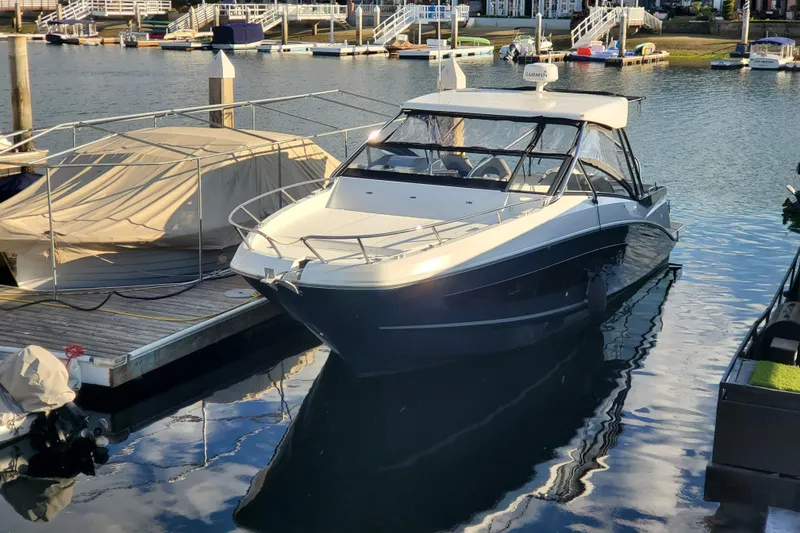 Slide: The Image of 2021 Beneteau Flyer 10 docked at a marina, reflecting on calm water. - 1
