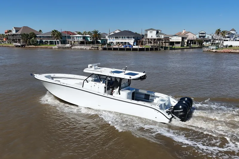 The Image of 2016 Yellowfin 42 Offshore boat cruising near waterfront homes. - 0