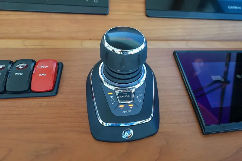 Slide: The Image of 2024 Back Cove 39O helm controls with joystick, wiper, and horn buttons. - 21