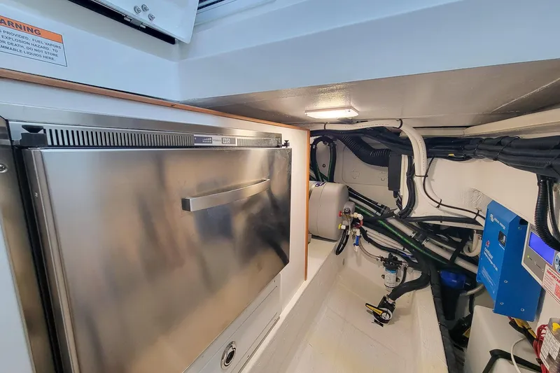 Slide: The Image of 2024 Back Cove 39O under helm storage area with Hybrid stainless drawer Refrigerator/Freezer , water heater, Battery charger and wiring access. - 23