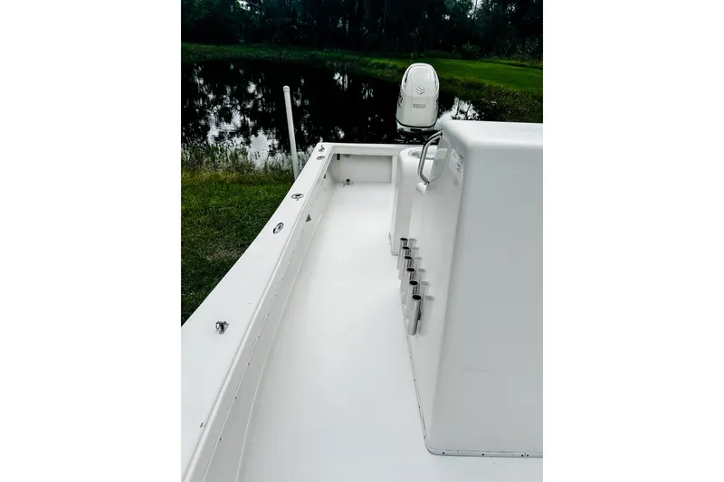 Slide: The Image of 2024 Hanson 23 boat interior with rod holders, near a serene lake. - 6