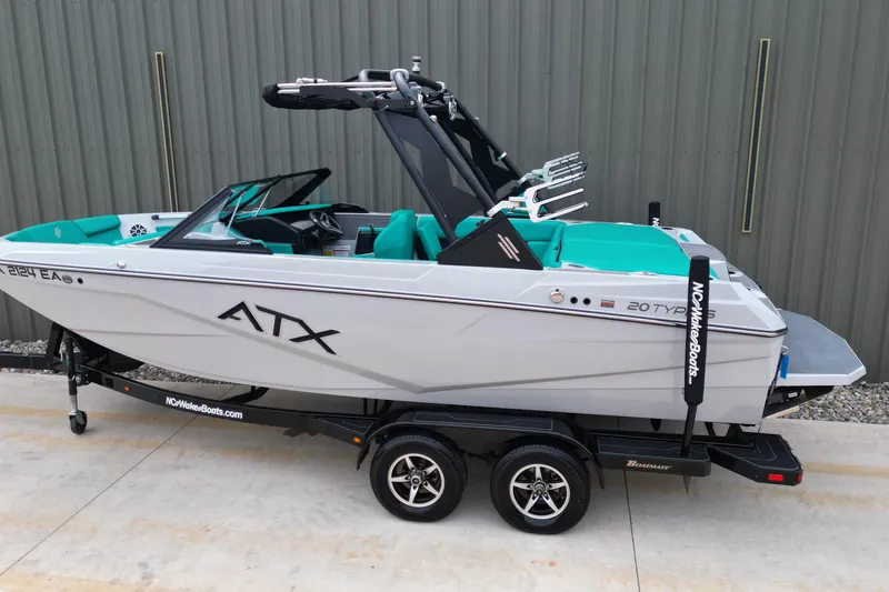 Slide: The Image of 2021 ATX Surf Boats 20 Type-S on trailer, teal interior, parked by a metal wall. - 6