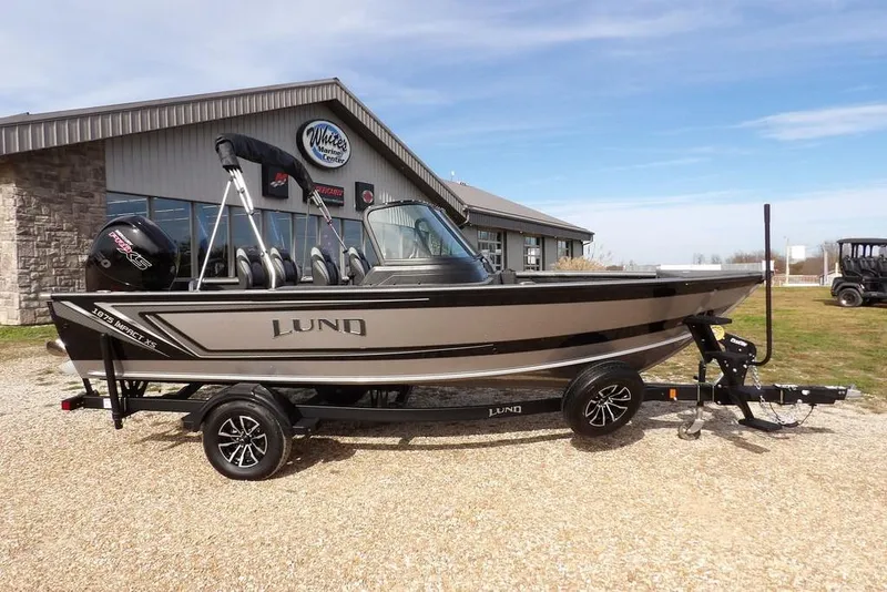 The Image of 2026 Lund 1875 Impact XS Sport boat on trailer outside marine center. - 0