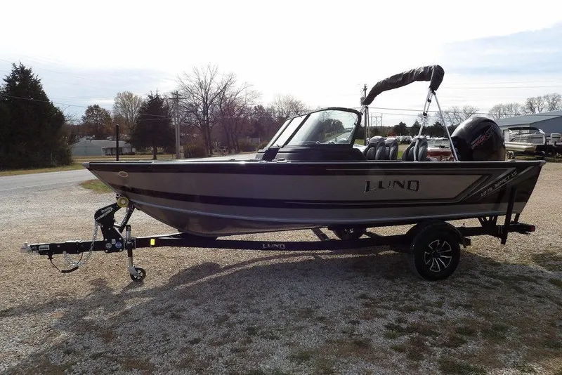 Slide: The Image of 2026 Lund 1875 Impact XS Sport boat on trailer, parked outdoors. - 2