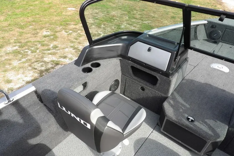 Slide: The Image of Storage compartment in 2026 Lund 1875 Impact XS Sport boat, featuring carpeted interior and speaker. - 31