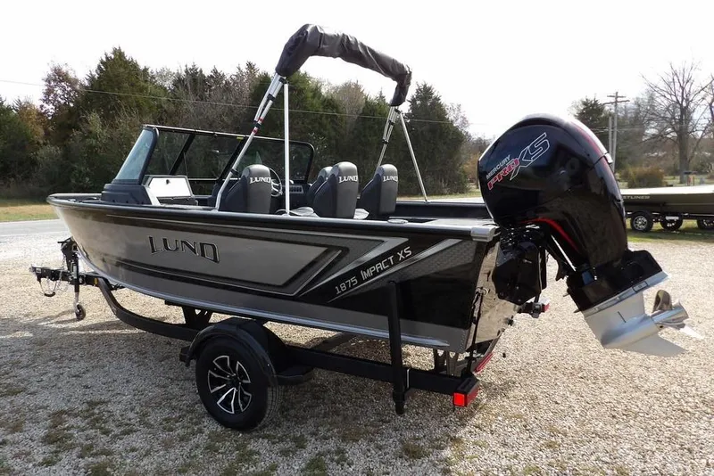 Slide: The Image of 2026 Lund 1875 Impact XS Sport boat on trailer, parked outdoors on gravel. - 5