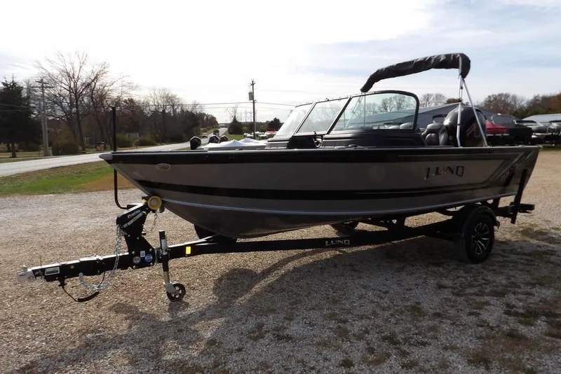 Slide: The Image of 2026 Lund 1875 Impact XS Sport boat with powerful outboard motor, parked on gravel. - 7