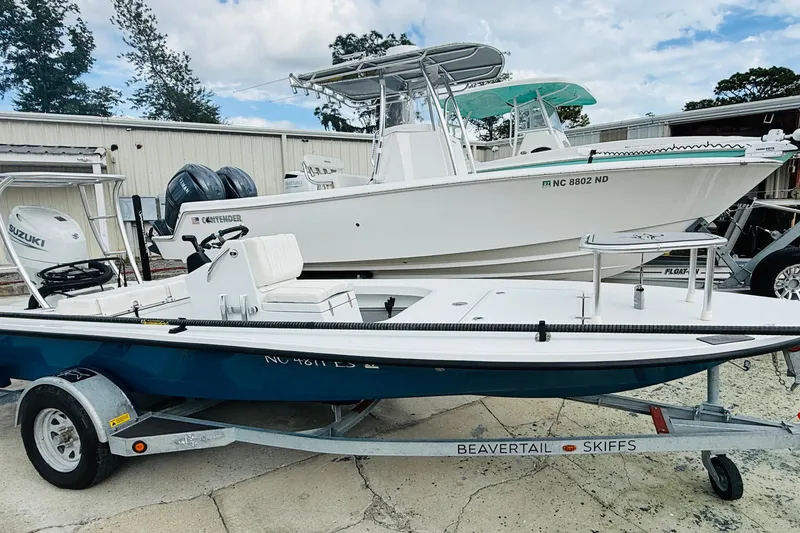 Slide: The Image of 2021 Beavertail Skiffs 18 Mosquito on trailer, parked beside a larger boat. - 3