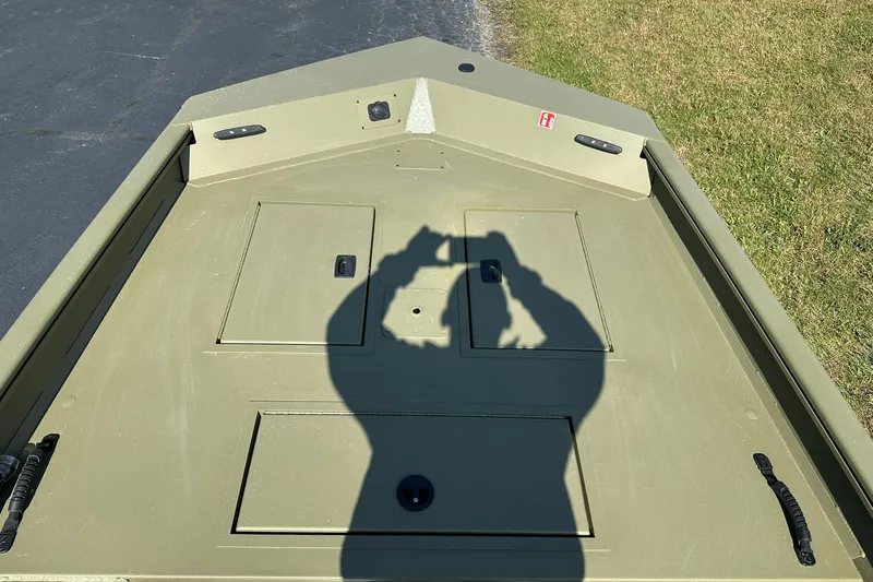 Slide: The Image of 2026 Lowe Roughneck 1860SC boat deck with shadow, parked on grass and pavement. - 9